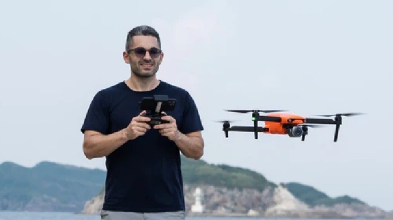 A drone pilot flying an orange drone