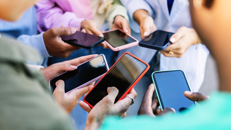 People standing in a circle using phones