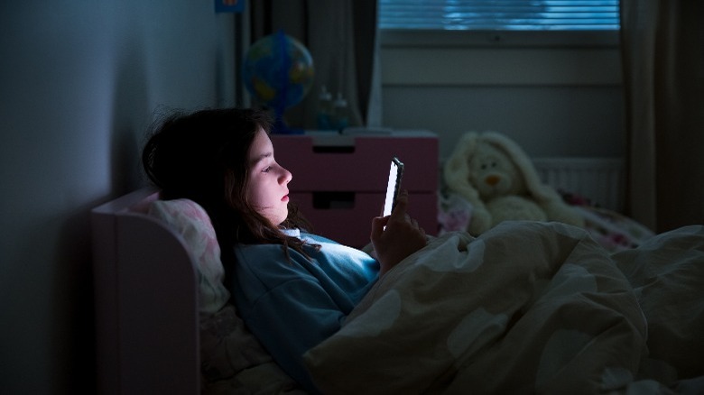 Kid using a phone in the bed