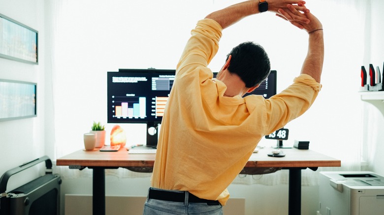 man stretching in front of standing desk