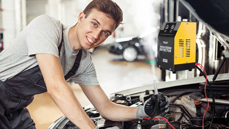 Car mechanic holding wires connected to tester