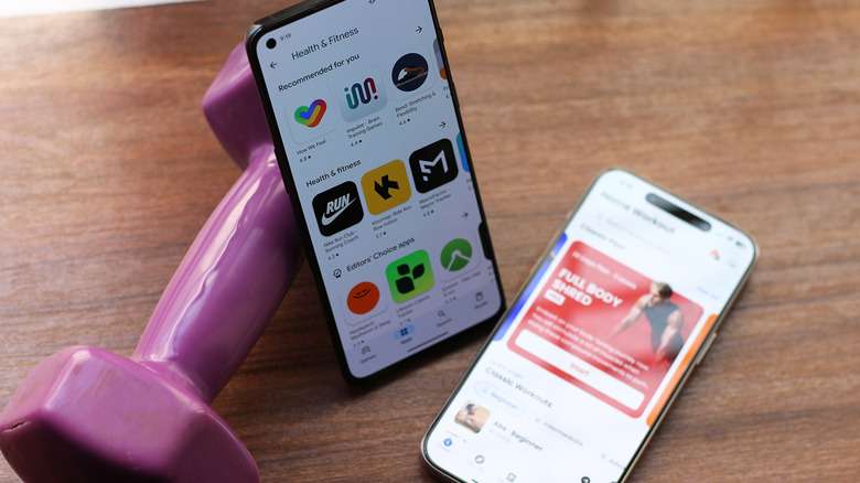 Fitness apps on phones next to a dumbbell