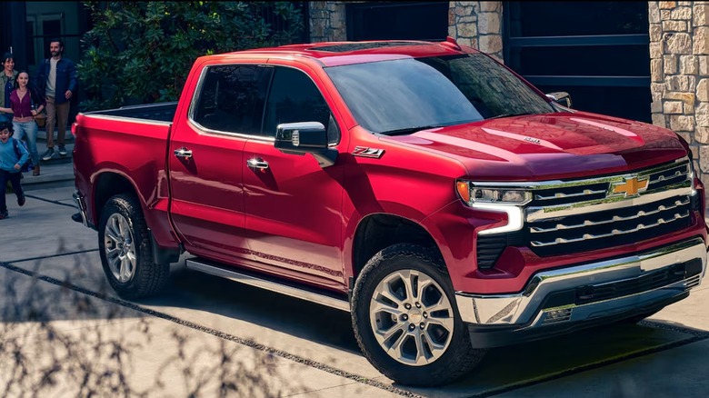 Red Chevrolet Silverado with family behind it