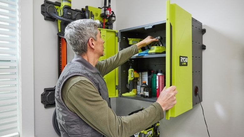 Man putting battery into the Ryobi Link wall-mounted cabinet.