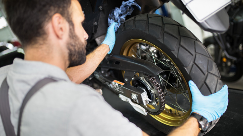 man adjusting motorcycle wheels