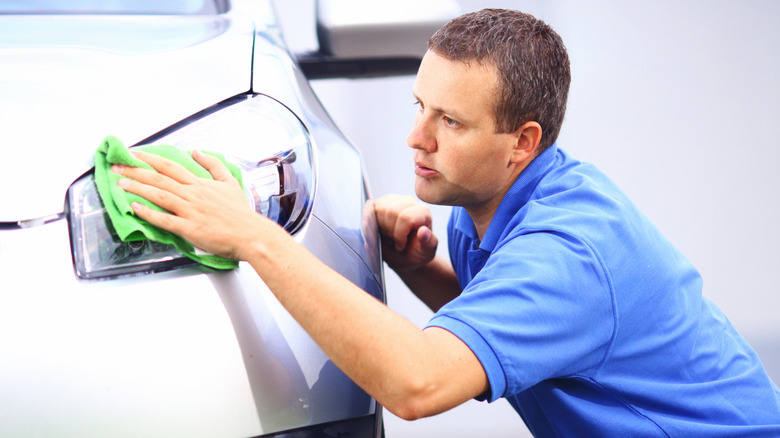 Man cleans a car's headlights