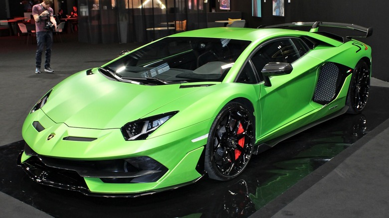 A green Lamborghini Aventador SVJ parked in showroom