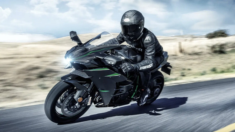 A rider in black riding a Kawasaki Ninja H2.