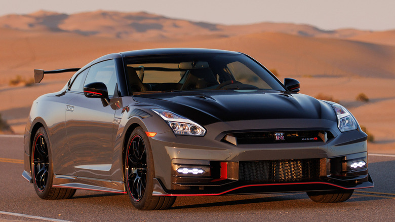 dark grey Nissan GT-R Nismo on track with hills in background