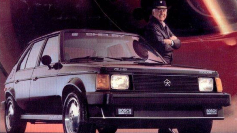 1986 Dodge GLH-S sales brochure cover art, featuring Dodge Omni GLH-S front-right three-quarter view with Carroll Shelby leaning on left side