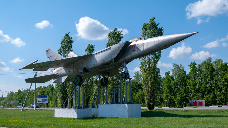 A silver MiG-25 stands mounted, its nose pointed toward the air