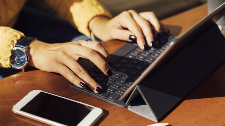 Girl typing on bluetooth keyboard and tablet