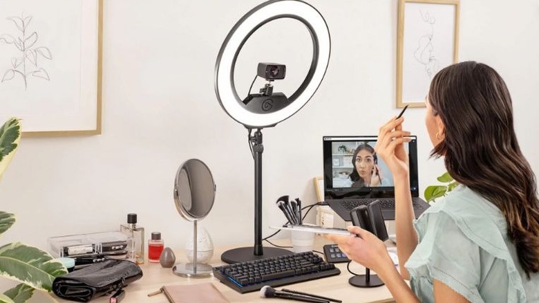 woman putting on makeup in front of Elgato ring light and laptop