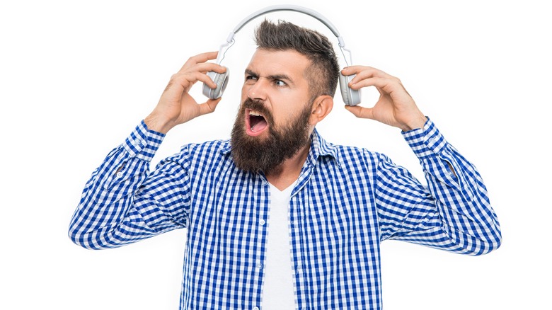 man upset by overly loud headphones