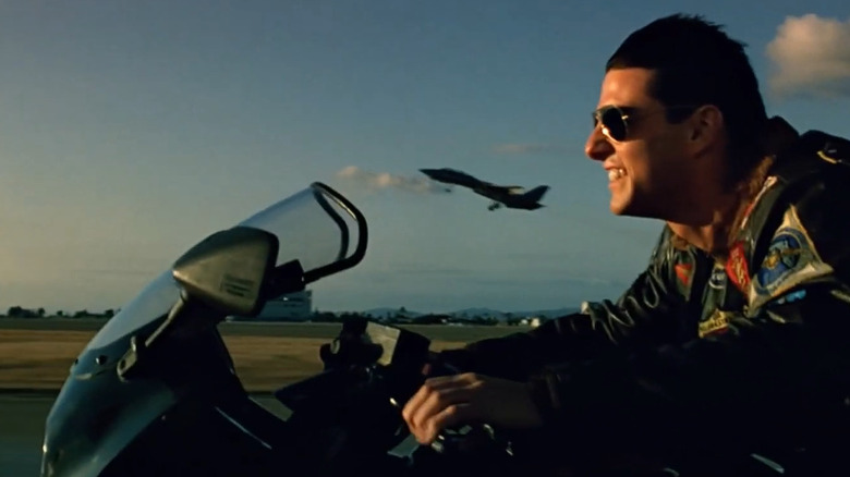 Maverick riding motorcycle next to jet