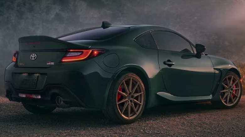 Green 2025 Toyota GR86 parked on misty mountain road with man walking in grass behind