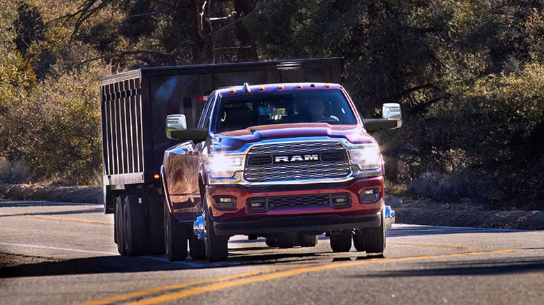 Red Ram pickup pulling large construction trailer uphill on curving road