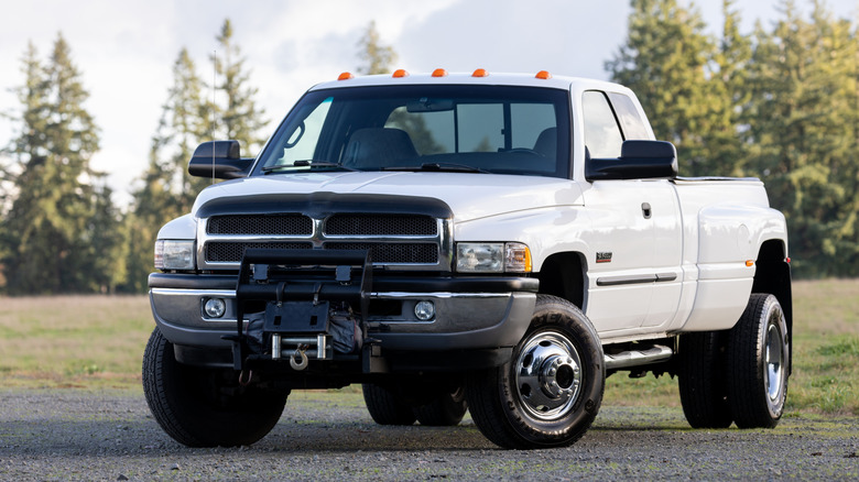 White Dodge Ram diesel parked on gravel with trees in the background