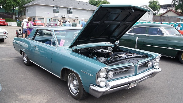 Blue 1963 Pontiac Grand Prix parked at car show with hood raised