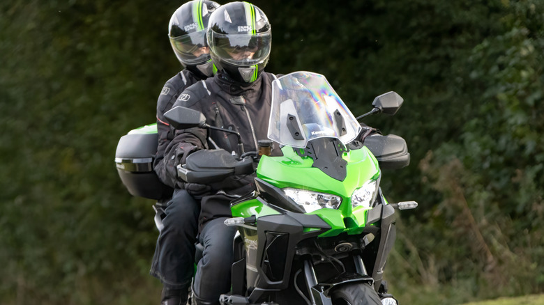 Two persons riding a Kawasaki motorcycle