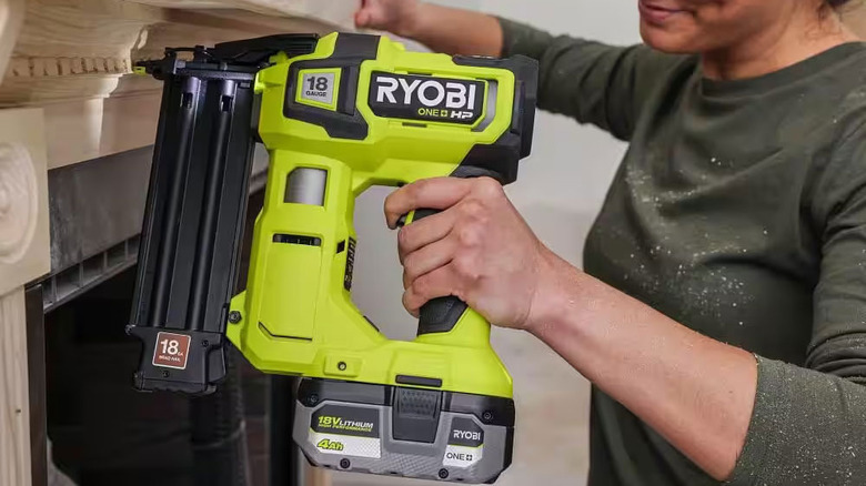 girl using a nailgun to attach an altar to a fireplace