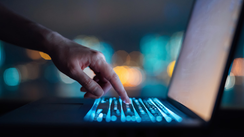 A hand pressing a laptop key