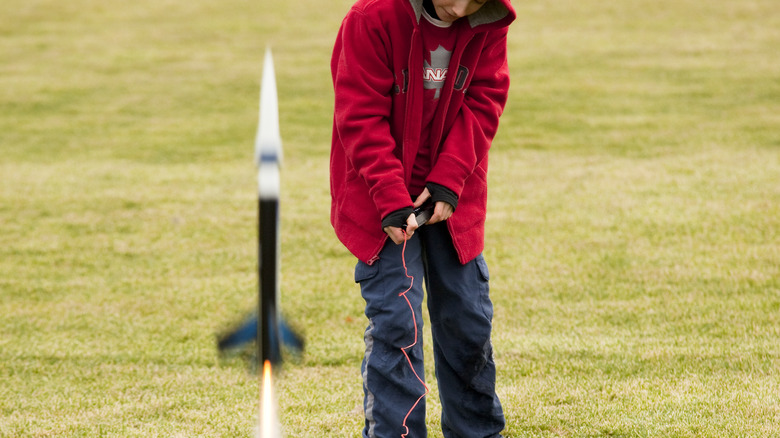 boy launching model rocket in park