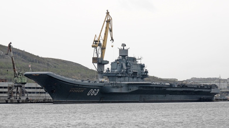 The Admiral Kuznetsov being serviced by a crane alongside a dock