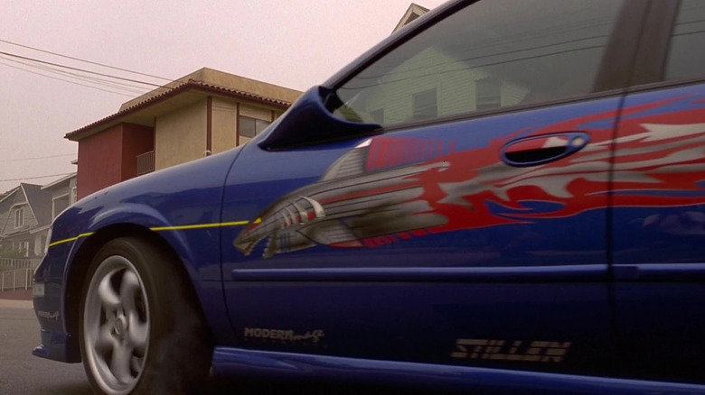 A Nissan Maxima on the street in The Fast and the Furious with a shark on fire design across the driver's side