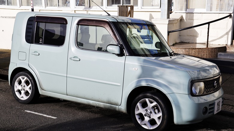 white Nissan Cube parked by the sidewalk