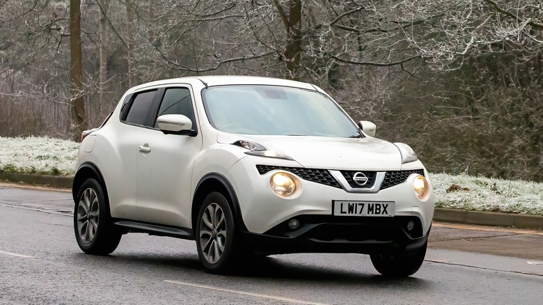 white Nissan Juke on on the road with light snow and trees