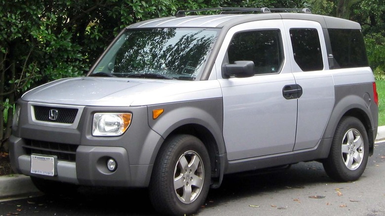 A silver and gray Honda Element on the side of a road.