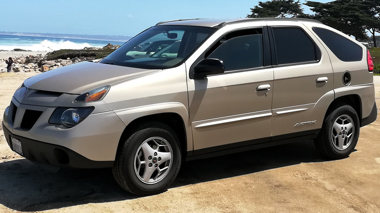 Pontiac Aztek parked next to a beach.