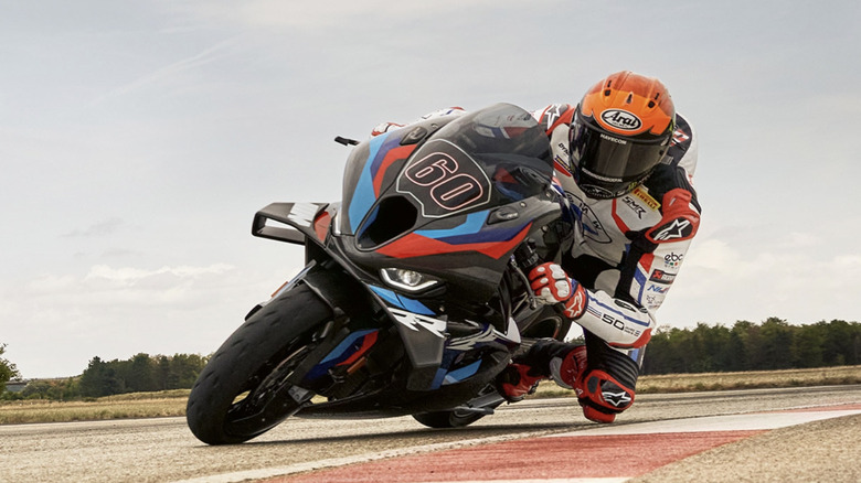 A BMW M 1000 RR with rider leans nearly to the ground