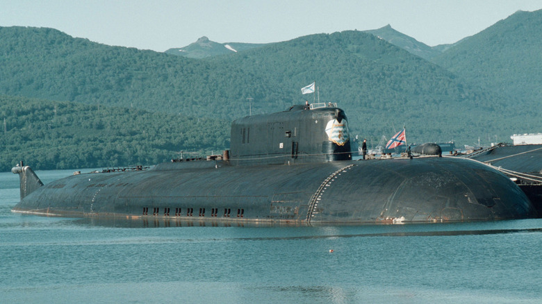 The Kursk docked in a harbor with lush green mountain in the background