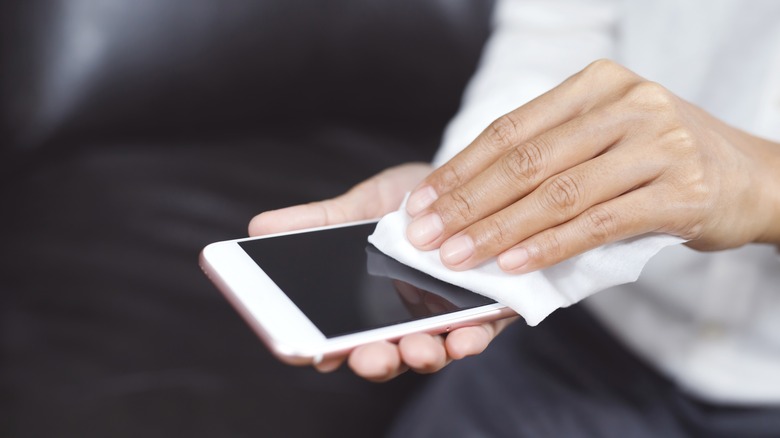 manicured hands cleaning an iPhone