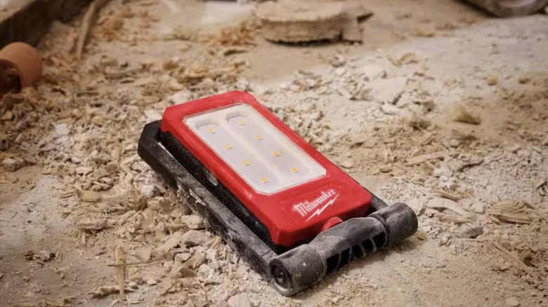 Flat flashlight on the ground covered in dirt