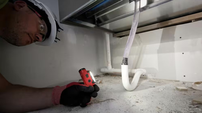 Person using a flashlight to see under a sink