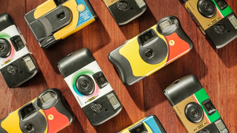 Several disposable cameras on a wooden surface