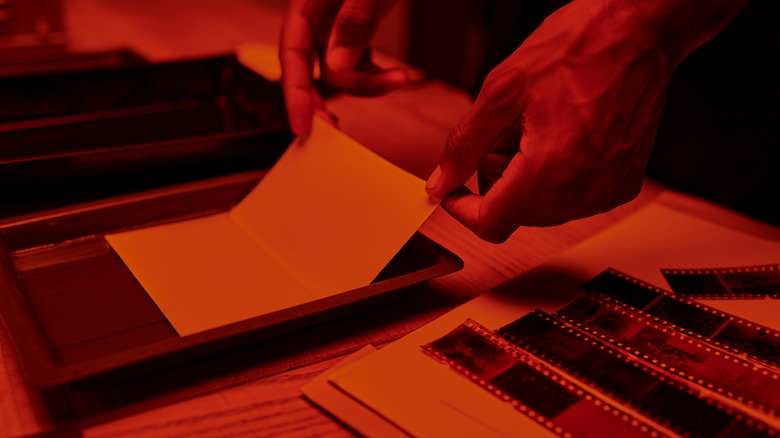 A person developing film negatives in a darkroom.