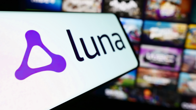 Luna logo on smartphone in front of out of focus TV showing Luna UI