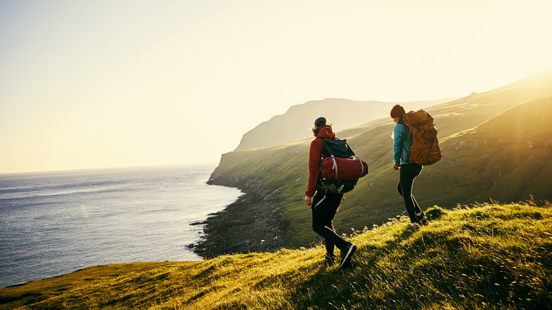 couple backpacking on oceanside cliff  