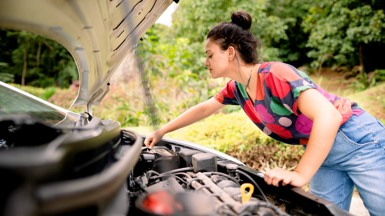 Woman looking under car hood