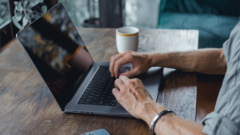 man using a macbook in a coffee shop