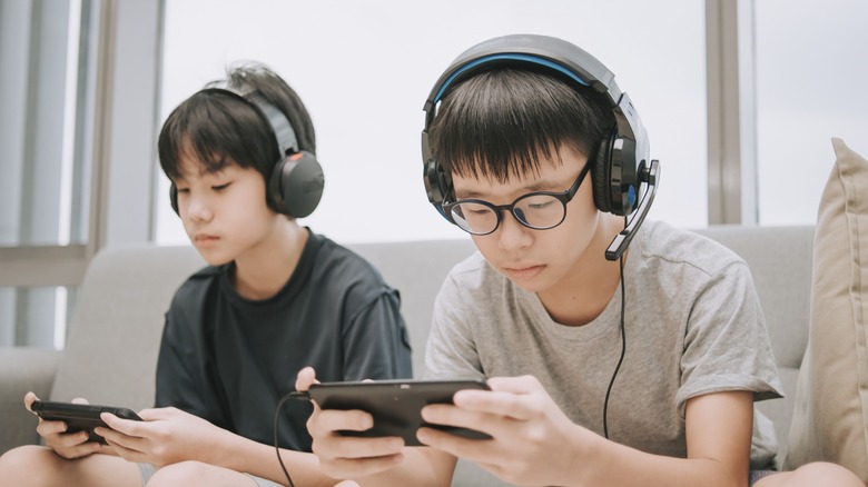 Two young boys playing mobile games