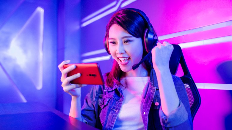 Young Asian woman holding a gaming phone and looking happy