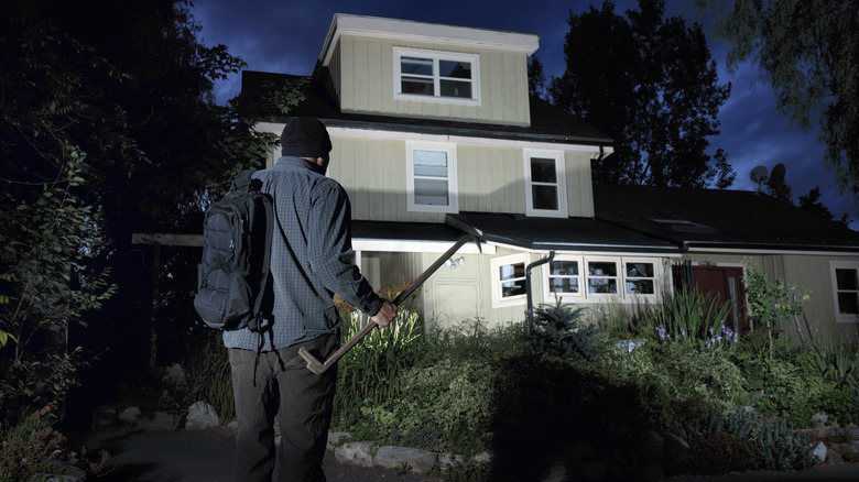 Thief walking up to well-lit house