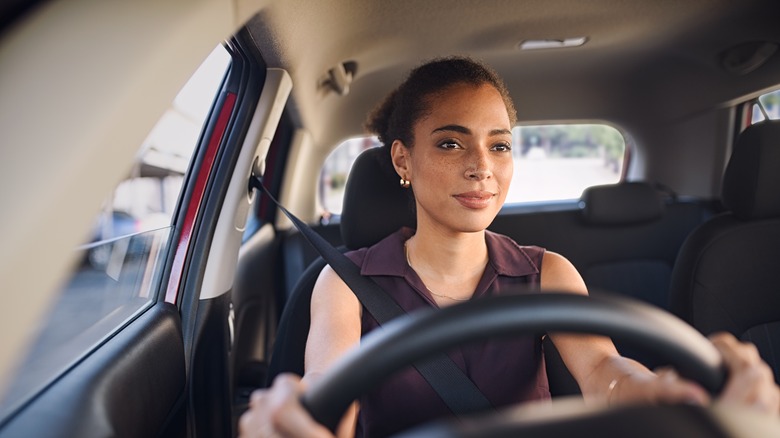 woman smiling while holding a steering wheel