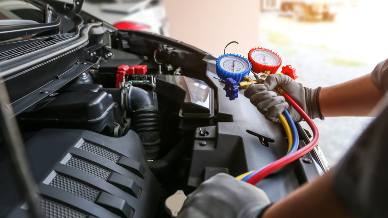 Hand of car mechanic technician use meter to check car air conditioner system