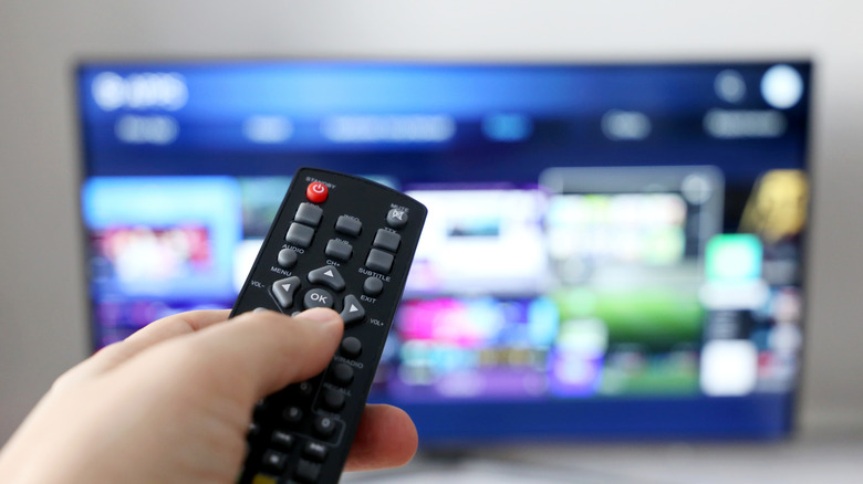 person holding remote pointing towards a TV